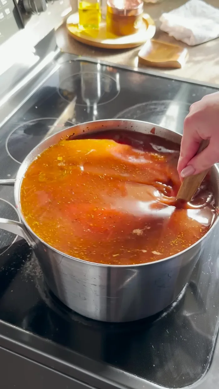 Add beef stock, three types of tomatoes (whole peeled, crushed, and puree), and parmesan cheese rind.