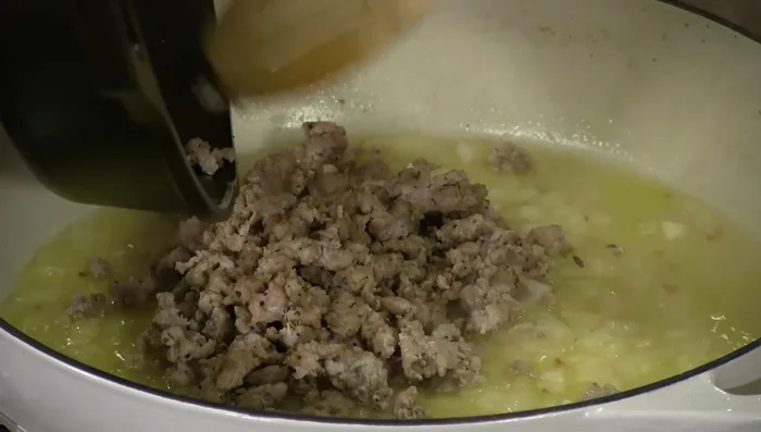 Add Italian sausage (crumbled), crushed tomatoes, and simmer until sauce thickens.