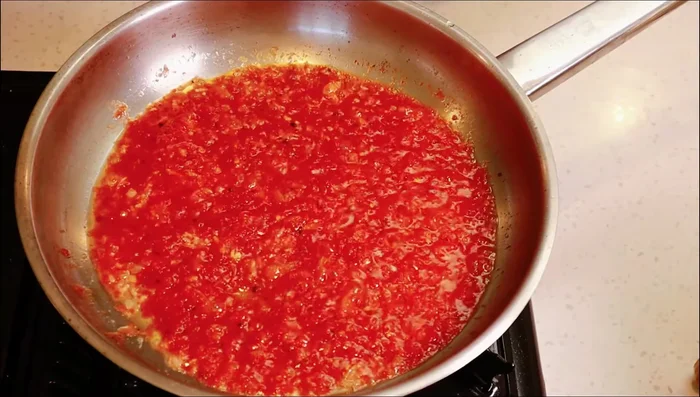 Crack 2 eggs into the tomato mixture.