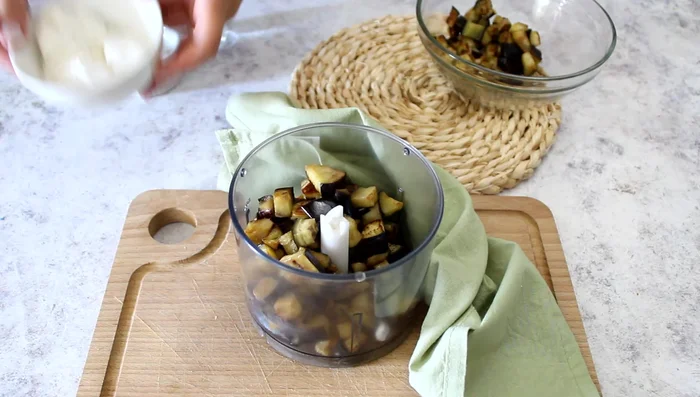 Blend the cooked eggplant (reserve some for garnish), ricotta cheese, salt, 2 basil leaves, and a tablespoon of water until smooth and creamy. Add more water if needed to achieve desired consistency.