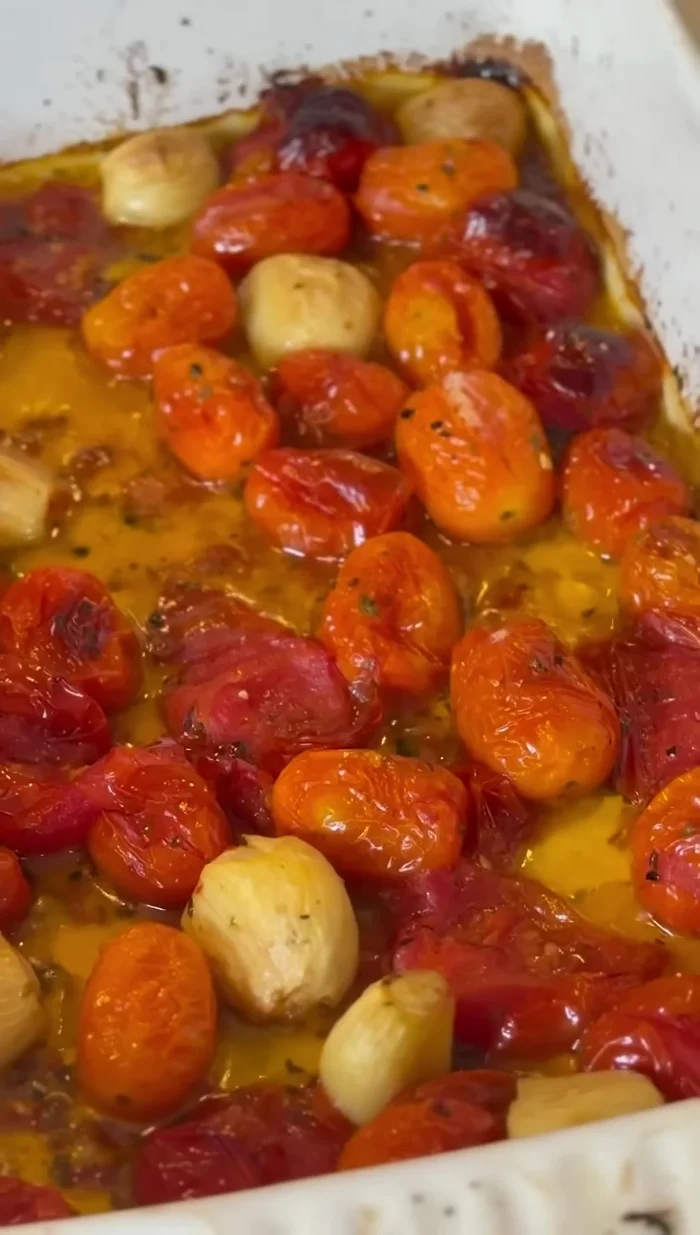 While the crust bakes, prepare the cherry tomato sauce: Roast cherry tomatoes, garlic, and olive oil with seasoning until blistered. Add basil.