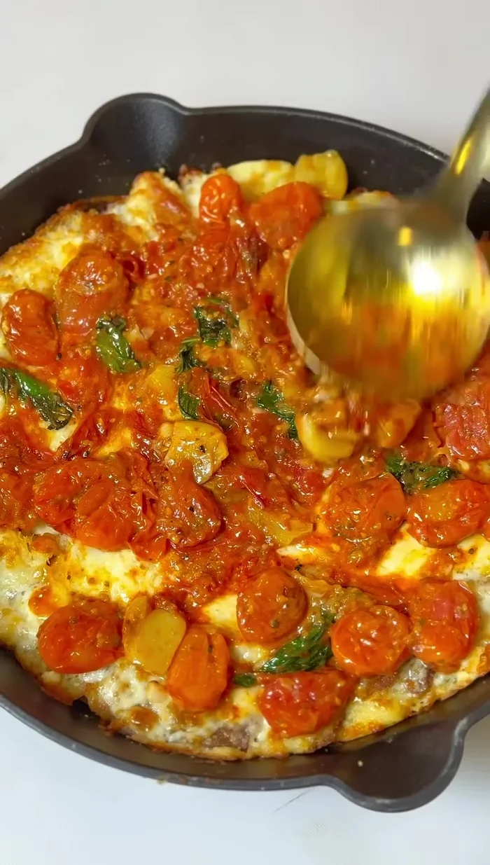 Once the crust is baked, top it with the cherry tomato sauce, mozzarella cheese, and more basil.