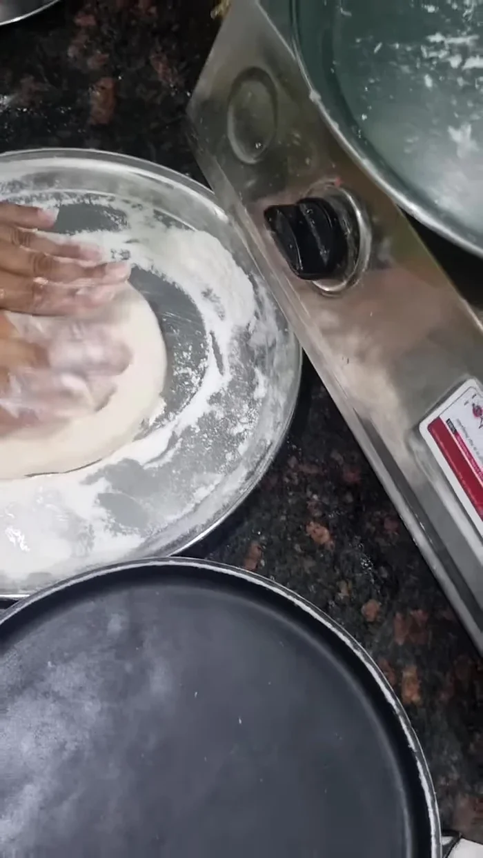 Place the flattened dough on a pizza surface. Slowly press it from the middle to create air bubbles.
