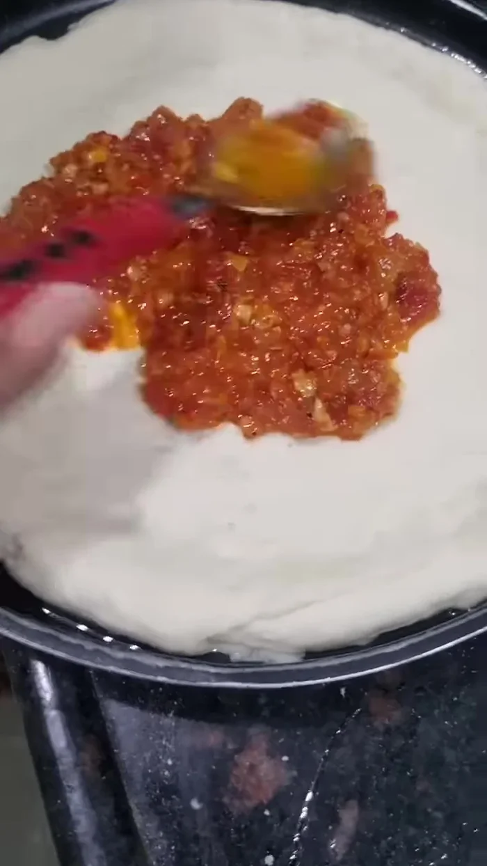 Spread a natural tomato puree over the dough.