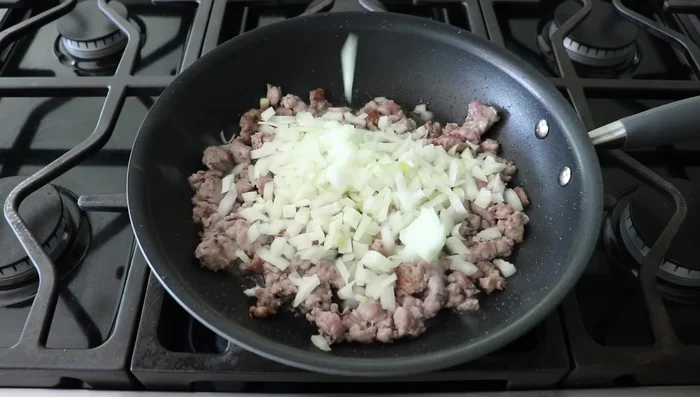 Add diced onion (and garlic, if desired) to the sausage. Season with salt, pepper, cayenne, and Italian herbs. Cook until onions soften.