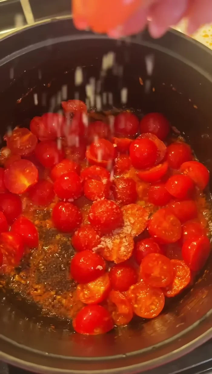 Add halved cherry tomatoes and sauté until soft, then gently mash them.