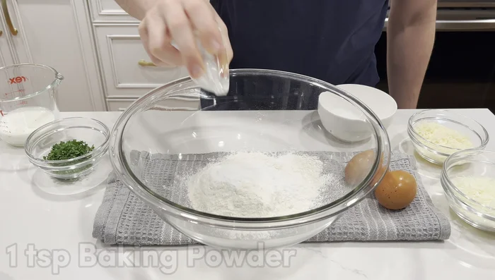 In a large bowl, whisk together flour, baking powder, 1/4 teaspoon salt, and a pinch of pepper. Make a well in the center, crack in eggs and pour in milk. Whisk, slowly incorporating flour, then mix until smooth.