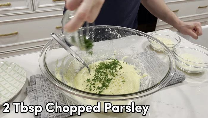 Add minced garlic, chopped parsley, grated Parmesan, and pecorino romano to the batter. Mix well.