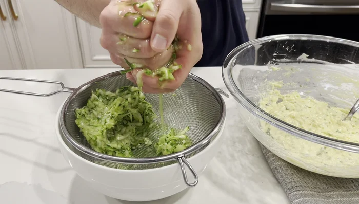 Squeeze excess moisture from the zucchini by hand, a small handful at a time, and add it to the batter. Mix until combined. Batter should be thick but pourable.