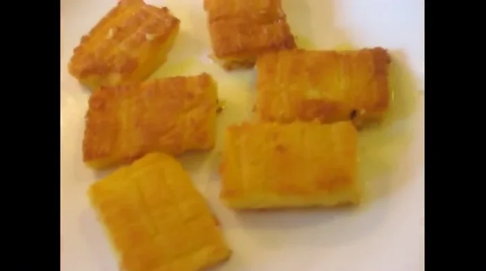 Transfer the fried polenta to a platter, grate mozzarella on top, and let it melt from the residual heat.