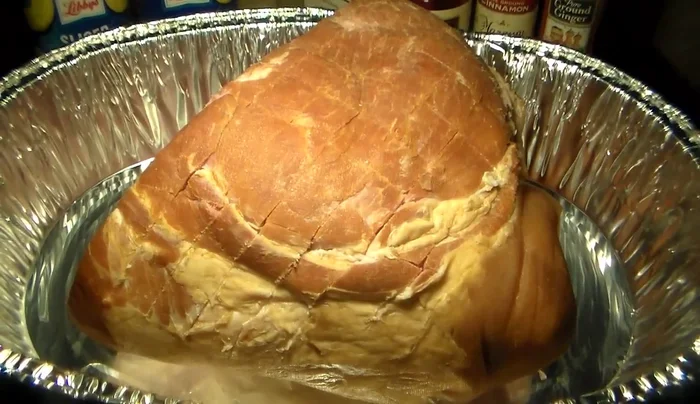 Coat the ham with mustard, then sprinkle with ground ginger, ground cloves, cinnamon, black pepper, and brown sugar.