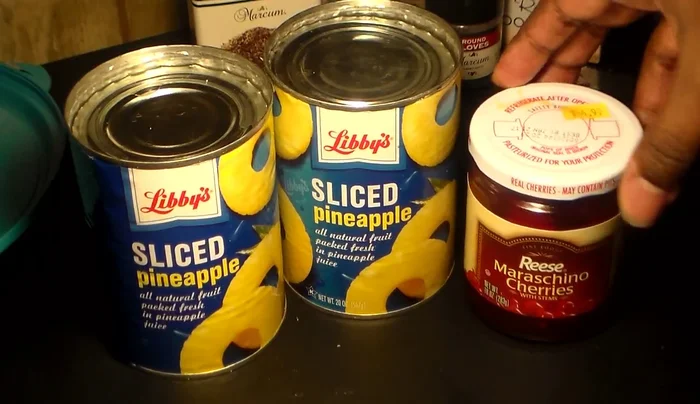 Remove pineapples from cans and cherries from the jar, reserving the juice from both.