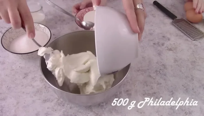 Prepare the cheesecake filling: In a bowl, mix 500g spreadable cheese, 250g ricotta, 60ml cream, 200g sugar, 2 eggs, vanilla, and lemon zest. Pour into the prepared crust.