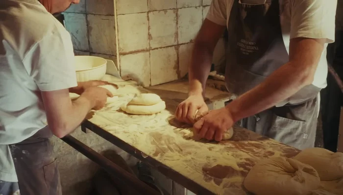 Shape the loaves: Shape the dough into large loaves with a distinctive bun on top, as shown in the video.