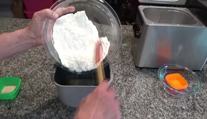 Make sure the kneading paddle is in the bread pan. Add the water, olive oil, salt, and sugar.