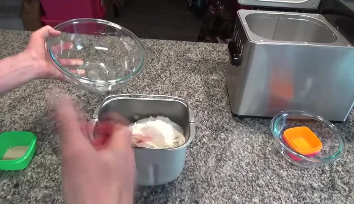 Add the flour to cover the liquid. Make an indentation in the flour. Then add the yeast. If the yeast makes contact with the liquid, it will activate the yeast.