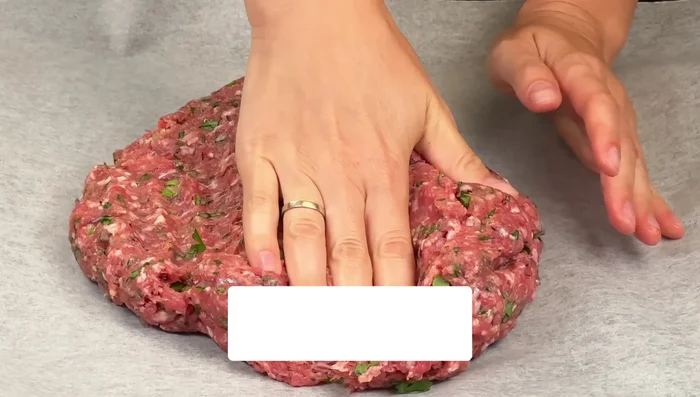 Spread the ground beef mixture thinly onto the prepared baking sheet, pressing down to create an even layer.