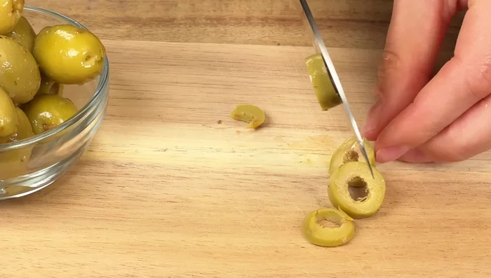 Arrange sliced green olives over the feta cheese.