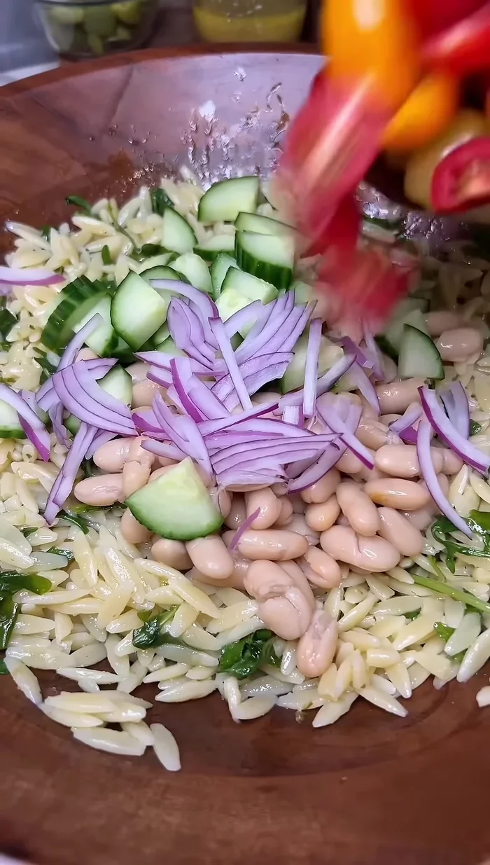 Add cannellini beans, cucumbers, thinly sliced red onion, cherry tomatoes, olives, and some feta cheese.