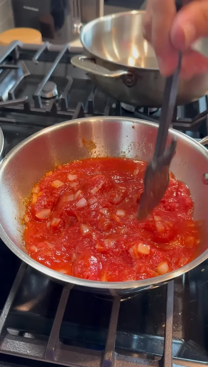 Add crushed tomatoes and break them up with a spatula. Season with salt.