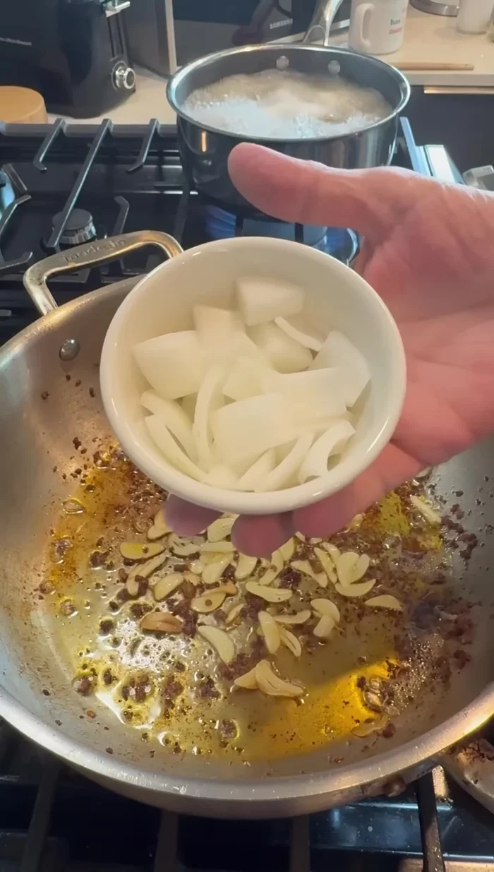 Add more sliced garlic and the remaining (large diced) onion to the pan with the fond. Stir and scrape the bottom to loosen the fond.