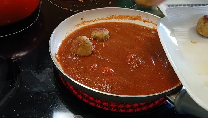 Add the browned bread balls to the sauce. Simmer on low heat for 5-7 minutes, or until heated through and the sauce has absorbed the seasonings. Stir occasionally.