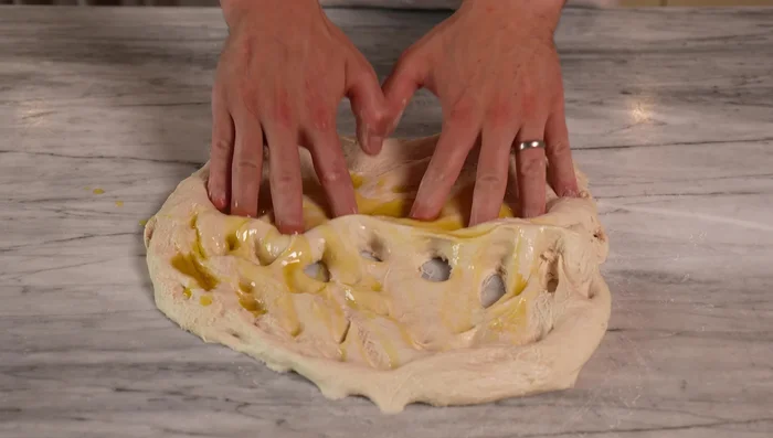 Add oil and mix: Add 20g olive oil and incorporate into the dough by folding and pressing. Keep a bowl of water nearby for easy handling.