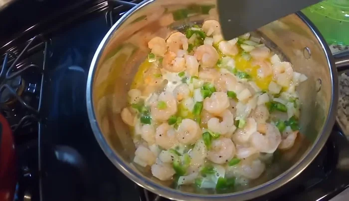 Sauté shrimp, green peppers, and onions in butter and minced garlic with salt and pepper in a saute pan over medium heat.