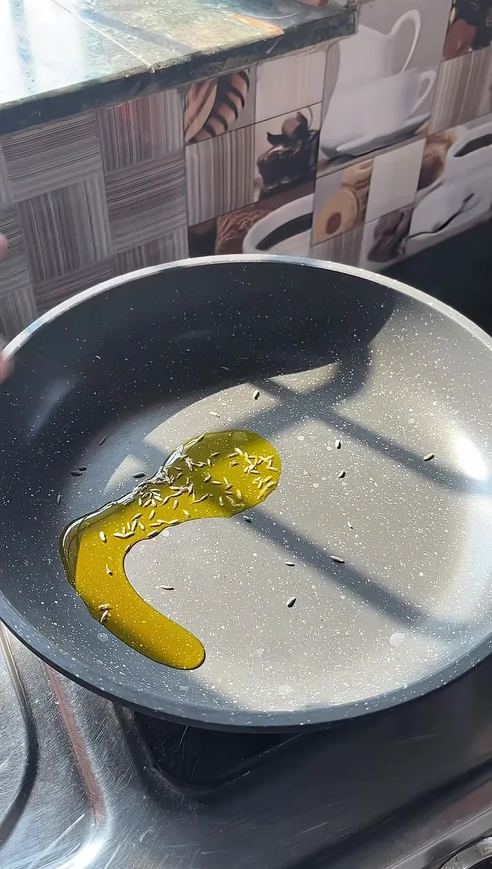 Heat oil in a pan and add cumin seeds, garlic, and green chilies.
