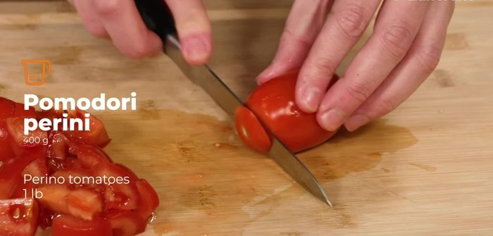 Remove the ends of the pear tomatoes and cut them into cubes using a serrated knife.