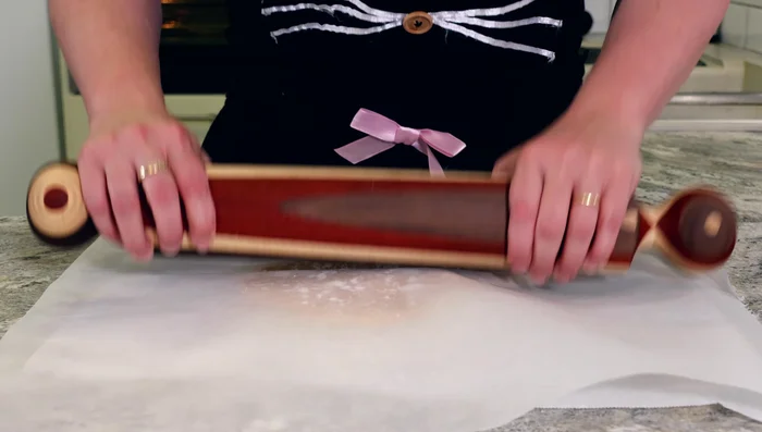 Lightly flour your surface. Roll out the larger dough piece between two sheets of parchment paper, then carefully transfer it into the tart tin.
